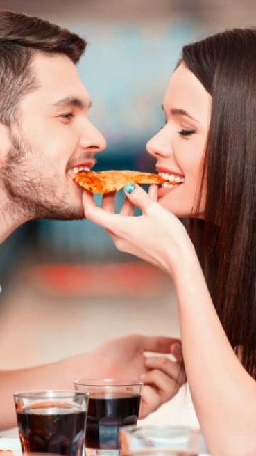 Zwei Personen beißen von einem Stück Pizza ab
